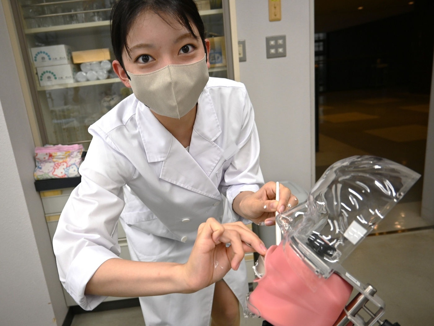 マネキンでの実習中にカメラを見つめる学生